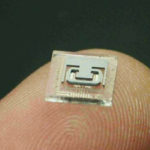 Fig 1. A decapped, MEMS chip, on a finger tip, showing the microtube and metal pattern.