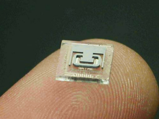 Figure 8. A decapped, MEMS chip, on a finger tip, showing the microtube and metal pattern.